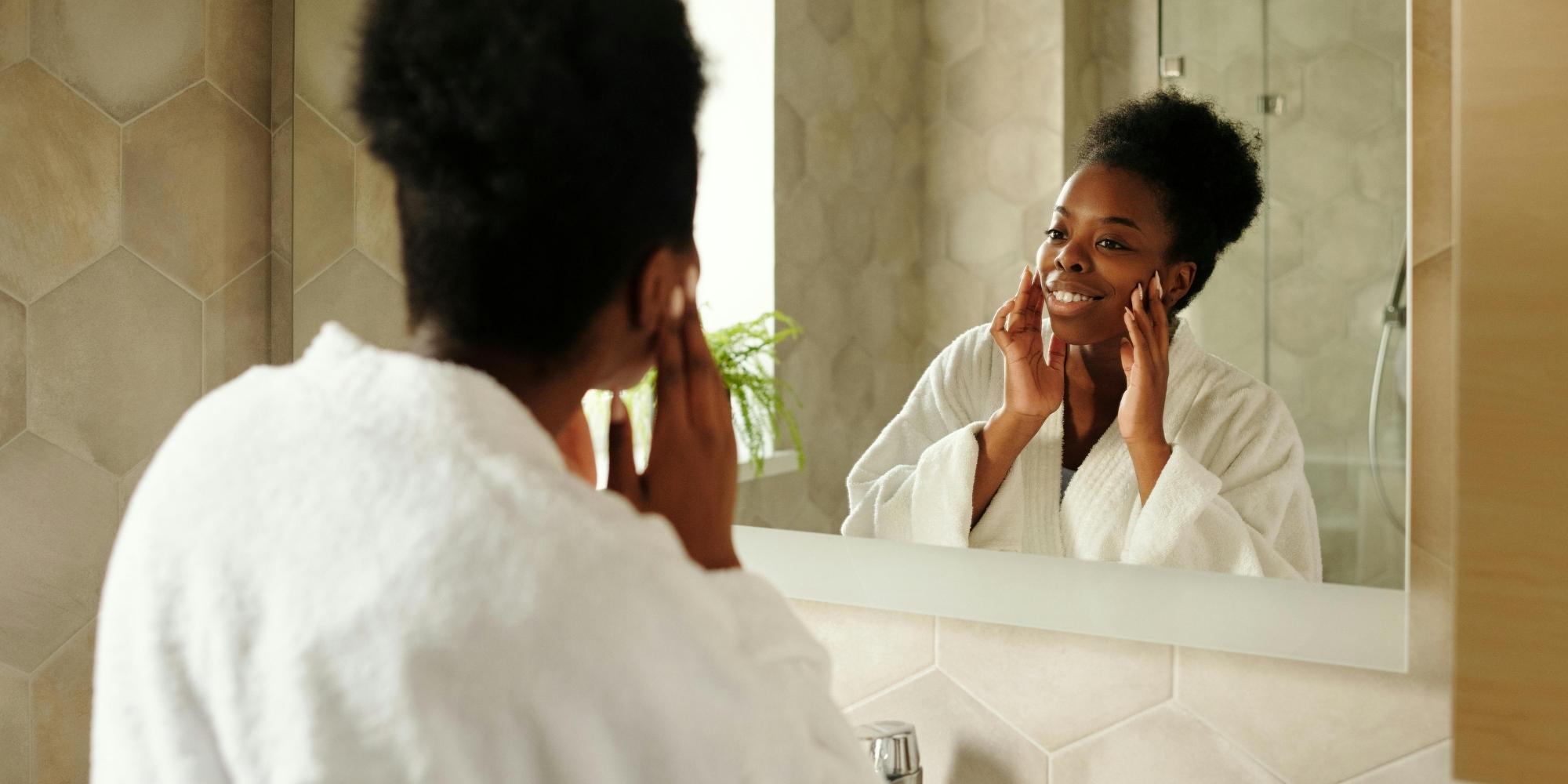 Femme ayant la peau foncée qui se regarde dans le miroir